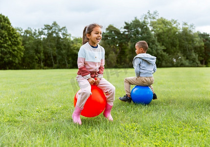 童年、休闲和人的概念快乐的孩子们在公园里跳跃着跳跃或弹跳球。在公园里快乐的孩子们在漏斗球上蹦蹦跳跳