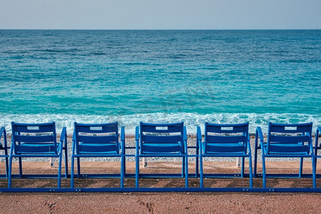 早上海滩上有著名的蓝色椅子长凳。很好，法国。法国尼斯海滩上著名的蓝色椅子