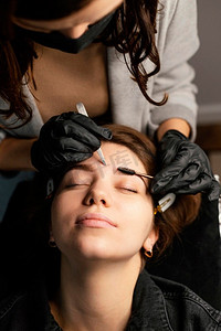 高角度女临床医生给女性做眉毛治疗