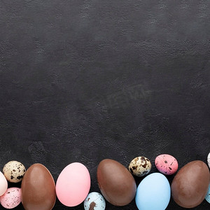 彩色扁平背景摄影照片_扁平铺彩色复活节彩蛋巧克力蛋