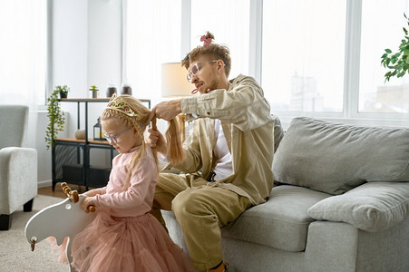 父亲与疯狂的发型和疯狂的脸鬼脸使头发的女儿，快乐的养育。父亲与疯狂的发型使头发为女儿