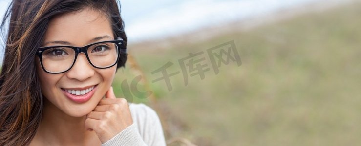 美丽的中国亚洲女孩或年轻女子的全景肖像，外面戴着眼镜，牙齿完美。全景网页横幅标题。