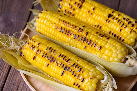 玉米食物，甜玉米熟在木板背景，成熟的玉米棒烤的甜玉米食物纯素晚餐或小吃—顶视图