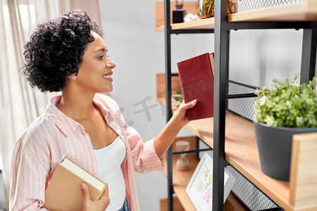 家庭改善和人的概念—快乐的微笑的妇女安排书架上的书籍。微笑的妇女安排书籍在书架在家里