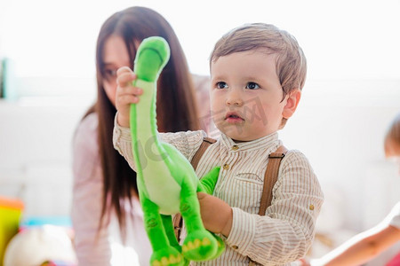 一个小男孩拿着绿色恐龙玩具