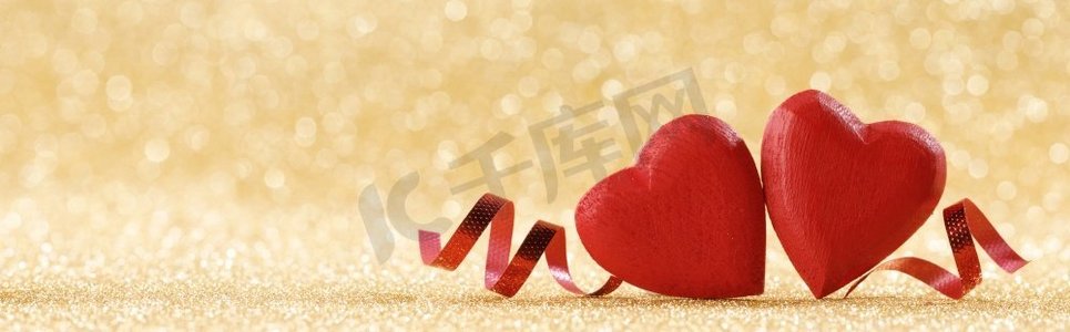 两个红色手工木心和丝带在金色明亮的闪光灯bokeh背景情人节。两颗红心在金色背景