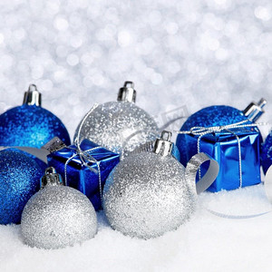 银和蓝色圣诞装饰在雪特写镜头。圣诞节装饰在雪地上