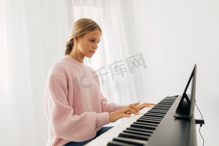 年轻的女孩玩键盘乐器家
