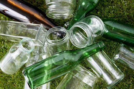 回收,垃圾处理,环境和生态概念 — 草地上用过的空玻璃瓶和罐子的特写