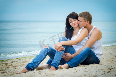 男孩和一个女孩在牛仔裤和白色T恤在海边
