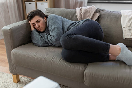 强调的女人摄影照片_心理健康、心理问题和抑郁症概念—强调妇女躺在家里沙发上。抑郁的女人躺在沙发上在家里