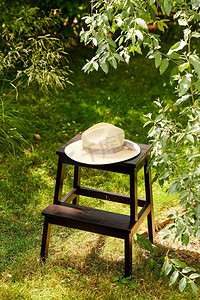 休闲与物件概念-夏园凳子上的草帽特写。夏日花园凳子上的草帽合影
