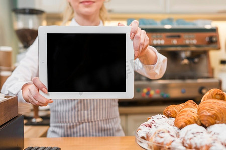 女性面包师显示数字平板电脑前烤羊角面包计数器