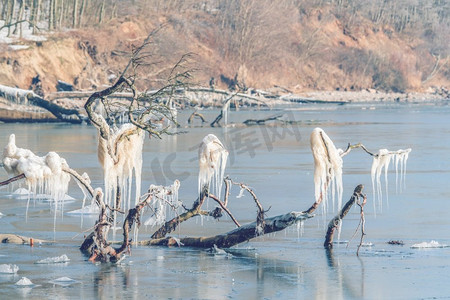 冬天结冰的湖面上树枝上挂着冰柱的冰雪景观