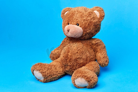 蓝色莫兰迪ppt模板摄影照片_软玩具和童年概念—棕色泰迪熊在蓝色背景。棕色泰迪熊玩具在蓝色背景
