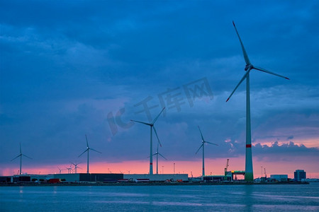 黄昏时分，安特卫普港的风力涡轮机为发电机提供动力。比利时安特卫普安特卫普港口的风力涡轮机在晚上