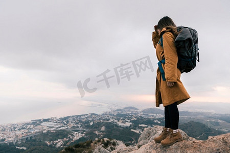 有她的背包的年轻妇女站在山顶看田园诗般的看法
