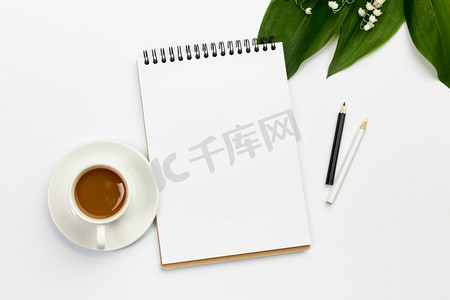 咖啡杯空白螺旋记事本彩色铅笔带叶花办公桌