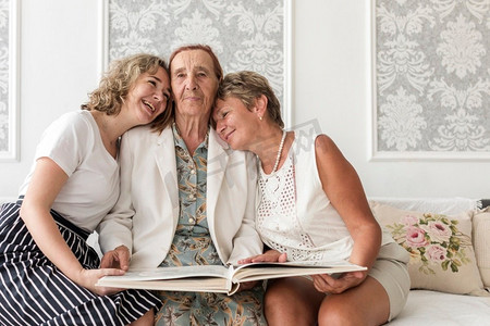 幸福三代女人拿着相册坐在沙发上