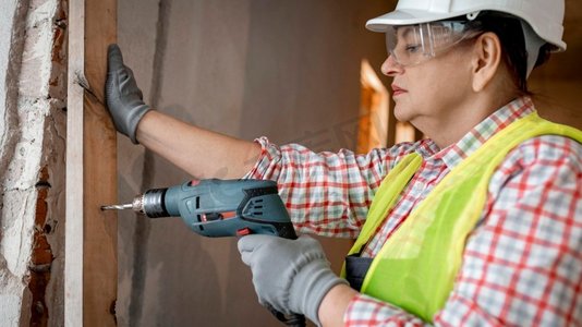 带头盔电钻侧视女建筑工人