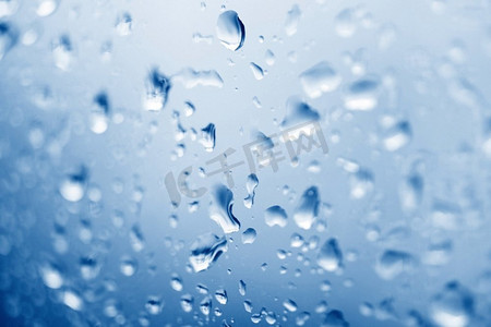 雨后玻璃摄影照片_水滴玻璃背景，雨后水滴自然蓝，雨季雨滴打在玻璃窗上
