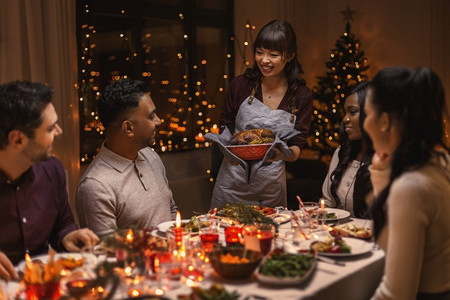 赢战鸡年摄影照片_节日和庆祝概念—多民族的快乐朋友在家里吃圣诞晚餐。快乐的朋友在家里吃圣诞晚餐