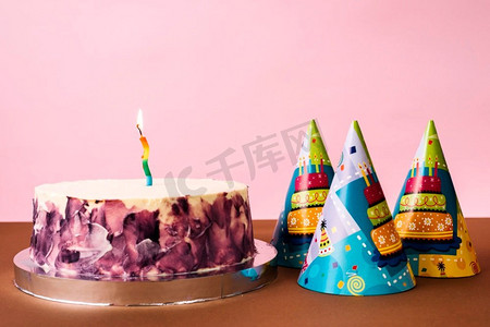 党帽子蛋糕与点燃蜡烛桌子对粉红色背景