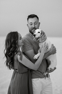 夏天衣服摄影照片_年轻夫妇橙色衣服与狗在沙漠白色的沙滩