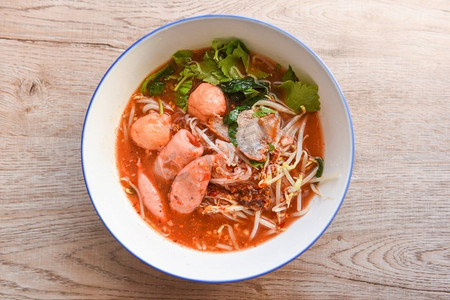 猪肉面菜单摄影照片_红色汤面猪肉与红色烤猪肉和豆芽蔬菜在汤碗在木桌，顶视图泰国和中国亚洲食物