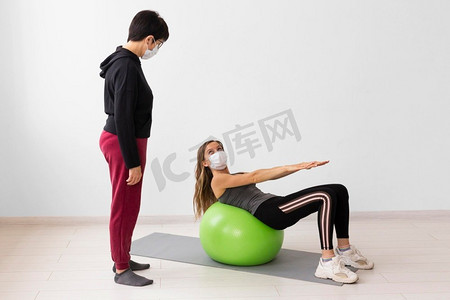女子戴口罩训练健身球