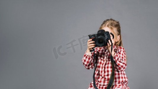 关闭了女孩拿着相机前面她的脸站在灰色背景