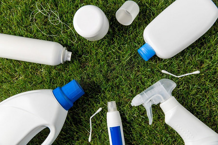 循环再造，环境及生态概念—草地上的塑胶及家居化学品废物特写。草地上的塑胶家居垃圾特写
