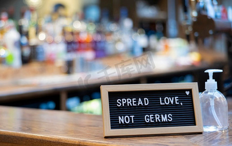 不是爱摄影照片_在酒吧柜台上的洗手液瓶旁传播爱而不是细菌