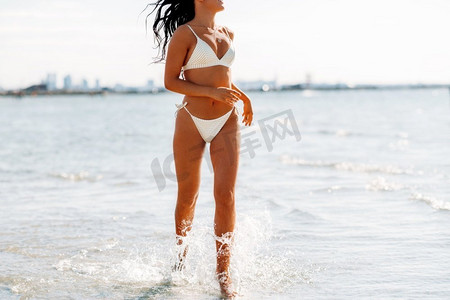 人，夏天和泳装概念—比基尼泳装快乐的年轻女子在水海滩运行。年轻女子比基尼泳装在海滩