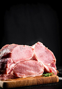 大块的生猪肉放在木板上。黑色背景。高质量的照片。大块的生猪肉放在木板上。 