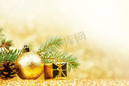 闪光绿色摄影照片_圣诞卡与冷杉树枝和装饰在金色闪光背景。圣诞卡