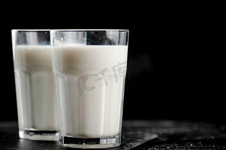 石板上的一杯新鲜牛奶。在黑色背景上。高质量的照片。石板上的一杯新鲜牛奶。