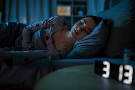 失眠表情报摄影照片_人，就寝时间和失眠的概念—清醒的少女躺在家里晚上。醒来的十几岁的女孩躺在家里晚上