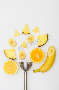 电动搅拌机与菠萝香蕉橙片隔绝的白色背景