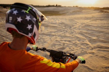 摩托越野MX车手戴着防护头盔骑在摩托车上看沙路。从肩膀上看。从肩上看摩托车上的MX车手