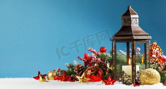 燃烧的圣诞灯笼和冷杉装饰在雪在蓝色背景与复制空间。圣诞彩灯装饰在雪