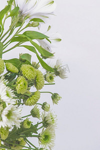 花边界与绿色和白色花瓣在白色背景。由百合和非洲菊组成的鲜花花束。前视图与复印空间。