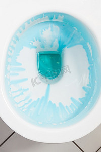 清洁和消毒概念。白色马桶，冲洗后用蓝色洗涤剂。白色马桶，配蓝色洗涤剂