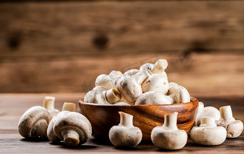 一个装满新鲜蘑菇的木盘子。在一个木制的背景。高质量的照片。一个装满新鲜蘑菇的木盘子。 