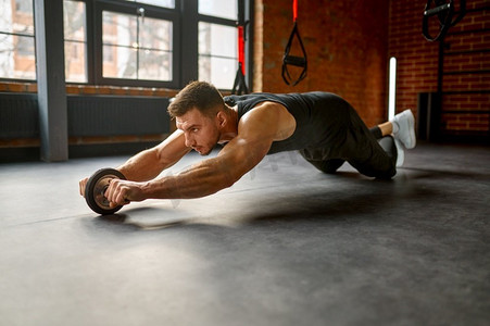 在体育俱乐部健身房用裸躯干 abs 轮训练的人.