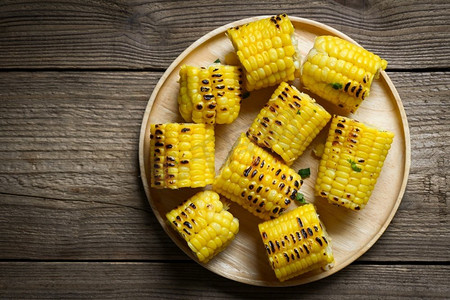 玉米食物，甜玉米熟在木板背景，成熟的玉米棒烤的甜玉米食物纯素晚餐或小吃—顶视图
