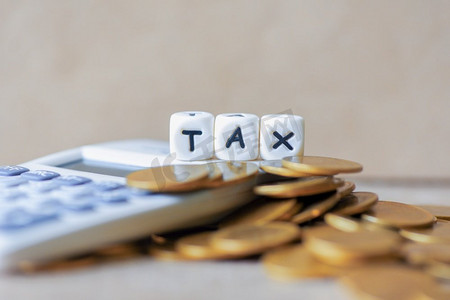 块字税在钱和计算器在木背景，在堆叠硬币财政税概念的税