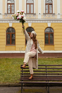 春天蝴蝶卡通摄影照片_快乐的女人长凳户外举行花束鲜花春天