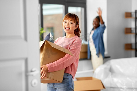 移动，人和房地产概念—快乐的微笑妇女与盒子在新家。带着箱子搬到新家的妇女