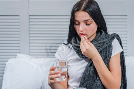 患感冒的妇女拿着玻璃水吃药